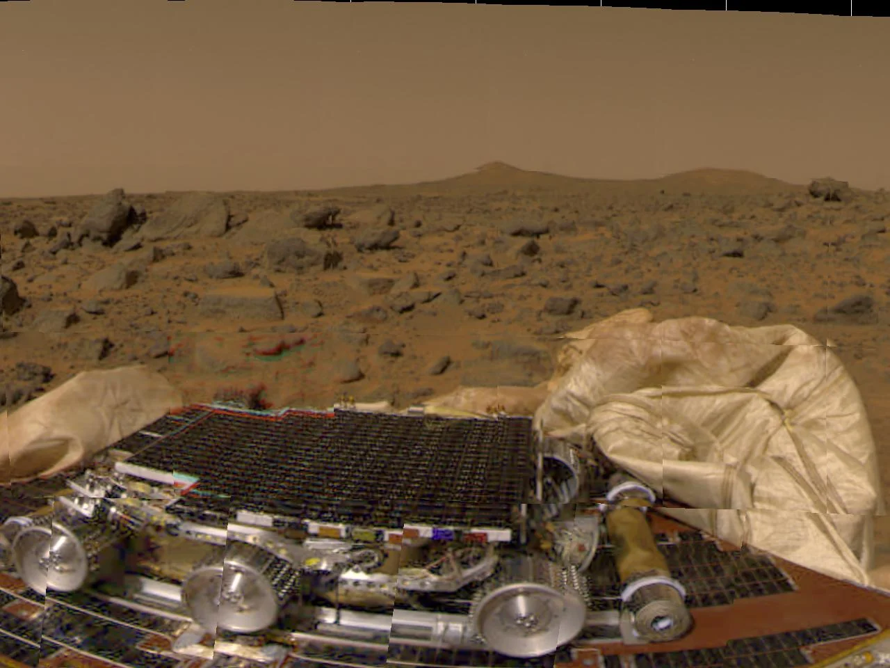 Sojourner sur un pétale du lander Mars Pathfinder après l’atterrissage du 4 juillet 1997, avec les airbags dégonflés et le terrain d’Ares Vallis